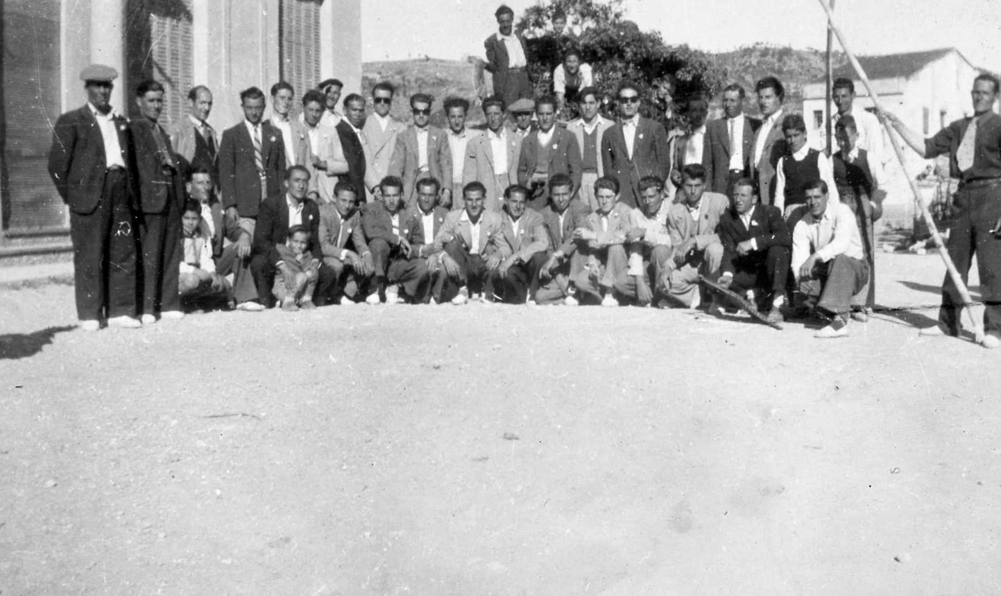 CARAMELLES Foto de grup amb l'Estudi al fons. De coneguts ajaguts: Joan de cal Teclo, Jaume de cal Jep, Joanito de cal Joan Guixà, Tonet del Cantó, Magí de cal Guixà, Agustí de cal Bertomeu i el Pepet de cal Meiem, de drets el Tonet de ca la Mundeta, Joan de cal Rei, Jaume de ca la Remei, Miquel de cal Miquel Codony i dalt del carro el Jaume de can Borràs.jpg