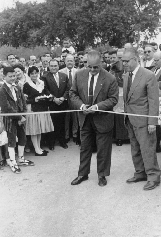 FENT LA CARRETERA Inauguració. 1960 Els pubills Santi Mató i Joanita Bernabé de Piera al costat de l'Alcalde Singla d'Igualada, el President Peix d'Obres Públiques de la Diputació tallant la cinta i l'Alcalde Mora de Piera. El Bisbe Modrego i mossèn Cucurull son pel darrere.jpg