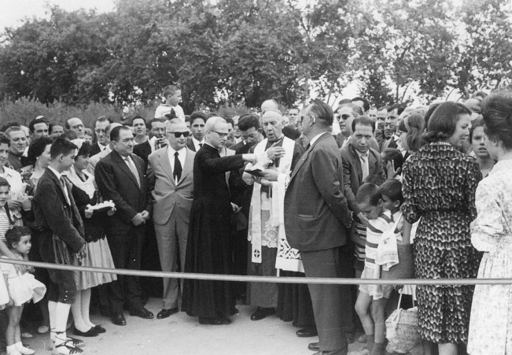 FENT LA CARRETERA Inauguració. 1960 Els pubills Santi Mató i Joanita Bernabé de Piera, l'Alcalde Singla d'Igualada, un desconegut amb ulleres fosques i un capellà, el Bisbe Modrego i mossèn Cucurull mig tapat pel President Peix d'Obres Públiques de la Diputació, també sembla reconeixer la Merceditas de cal Magí i l'Emma Romeu en primer pla a la dreta.jpg