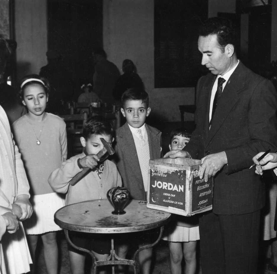 FESTA DE LA GUARDIOLA el Lluís de cal Batistó petant la guardiola entre la Mercè de cal Mericano i el Felicià de ca la Paulina davant l'Albertu de ca l'Albertu.jpg